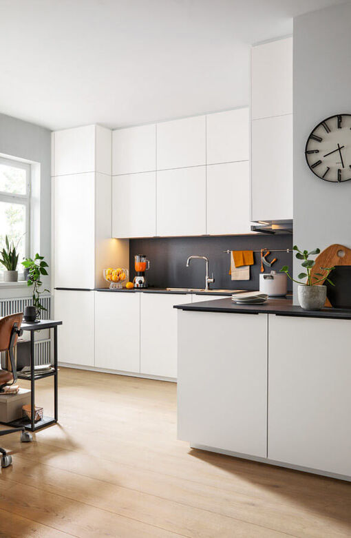 Kreative Küchenplanung für außergewöhnlich geschnittene Räume. Die matt-weißen grifflosen Fronten passen zu jedem Einrichtungsstil.